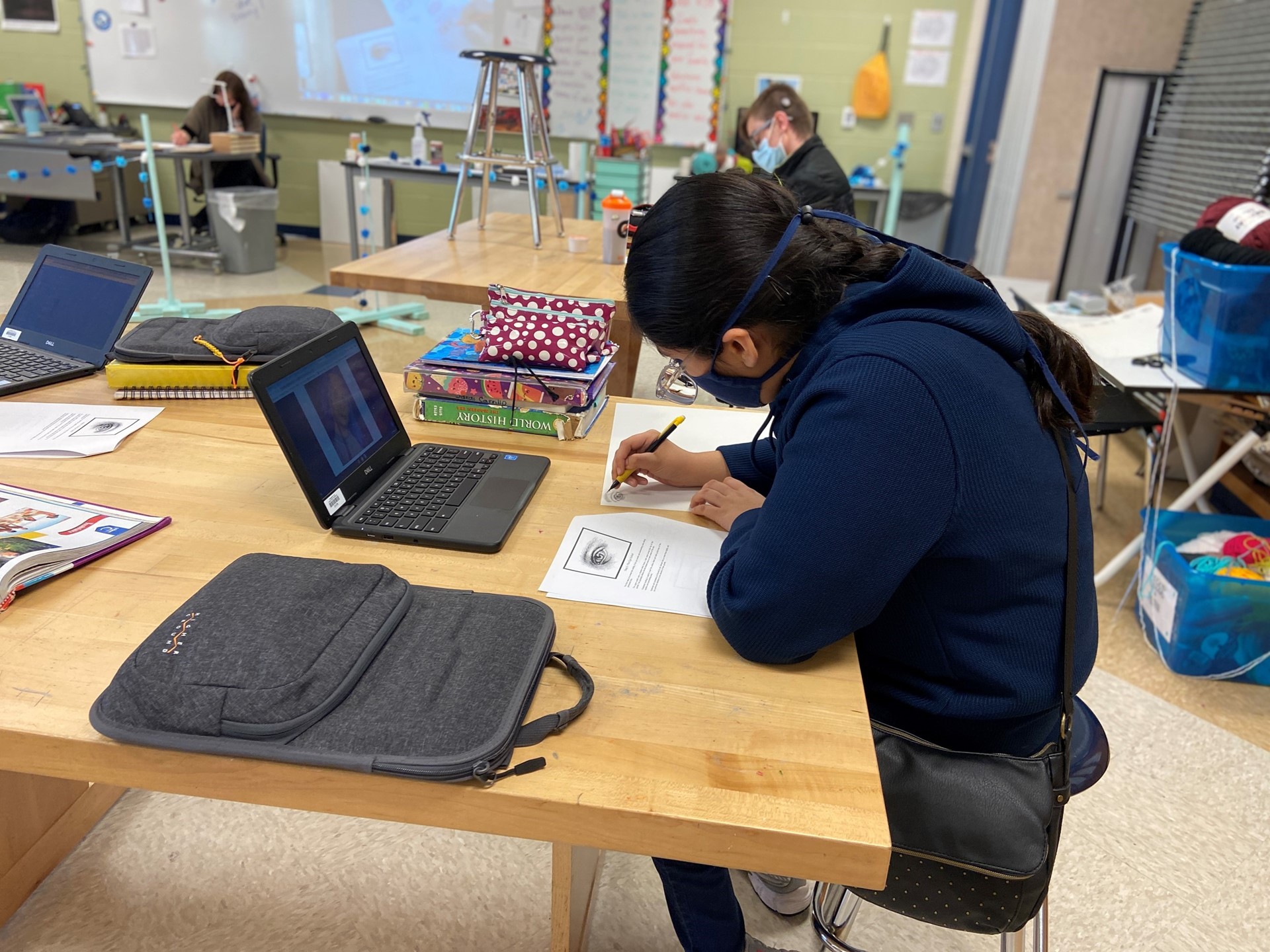 Students work on their art lesson with the teacher. 