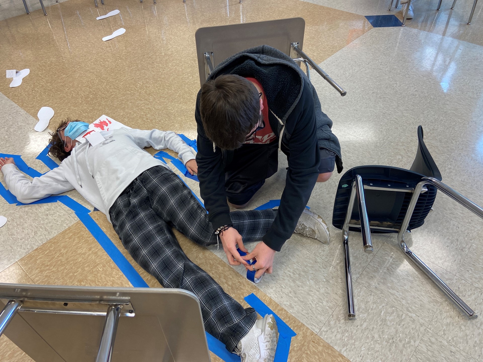 Students create a tape outline of a person in class. 