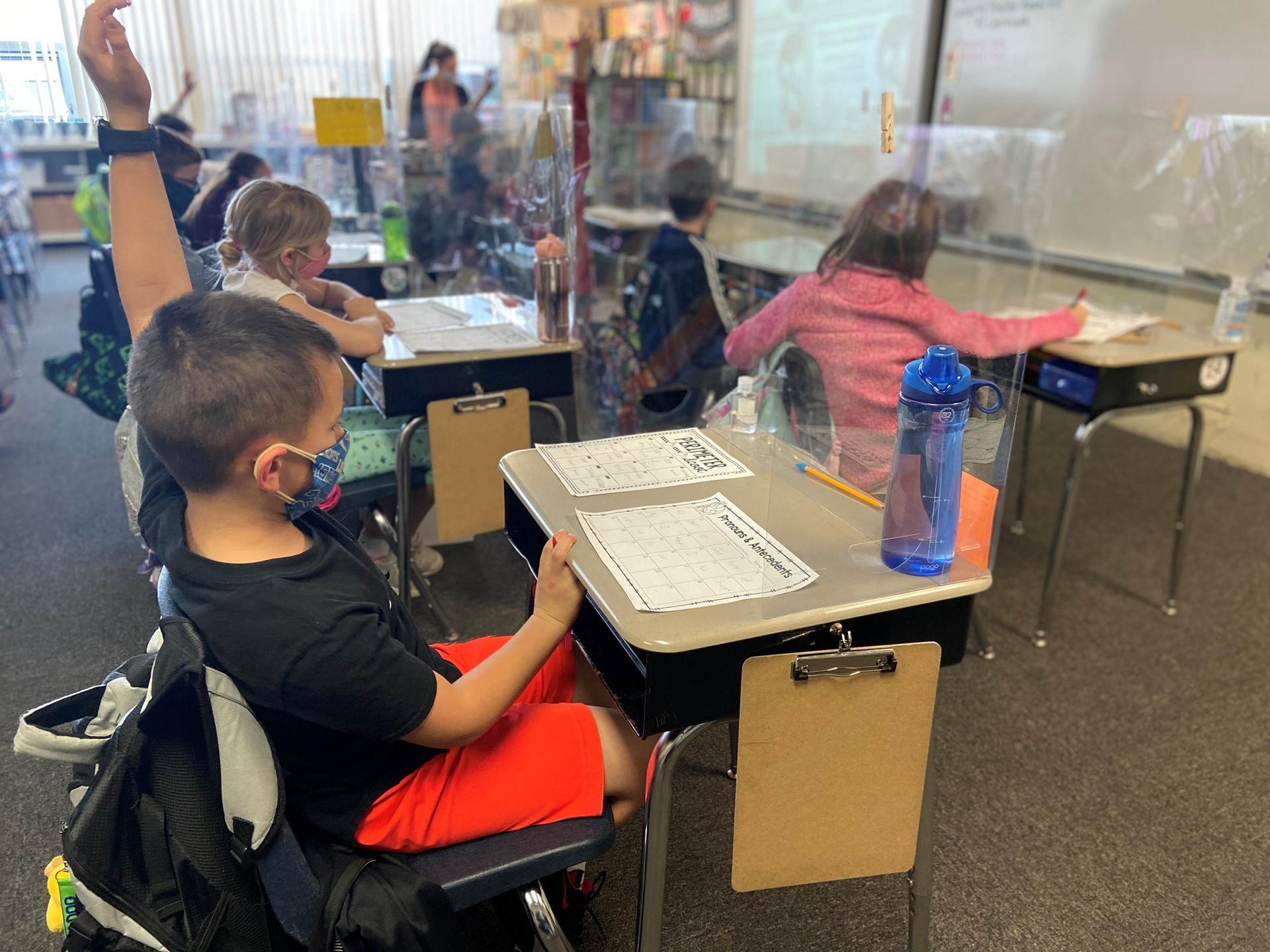 A student raises his hand in class to answer a question. 