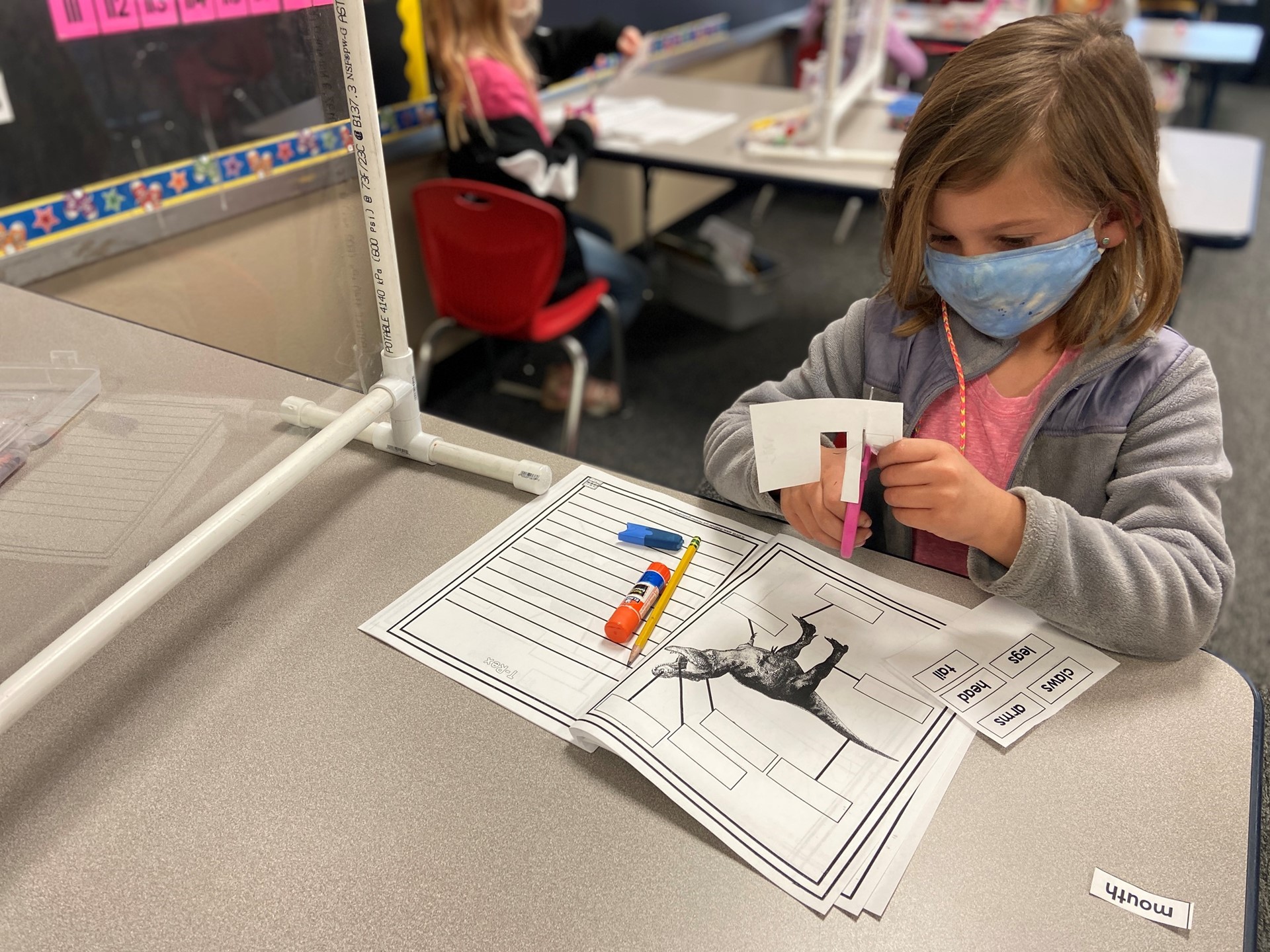 A student works to cut out labels for the dinosaur. 