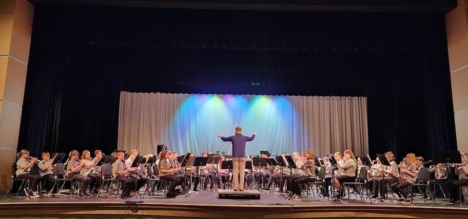 Beginning band members playing with the director standing in front of them. 